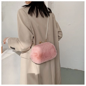 Detailed view of a pink faux fur shell bag featuring a luxury pearl shoulder strap and metal clasp