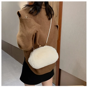 Winter plush crossbody bag with pearl strap and gold clasp on model's shoulder