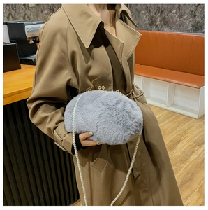 Detail of light gray faux fur shell bag with pearl strap worn over a khaki trench coat