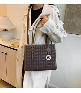 Detail view of brown quilted tote bag with silver V-pendant and adjustable strap