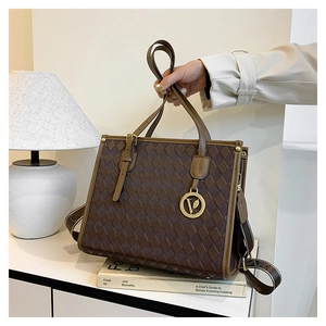 Close-up of brown quilted leather bag featuring a gold V pendant and adjustable strap