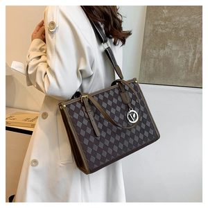Detail of vintage checkered tote bag featuring leather handles and gold V-shaped charm