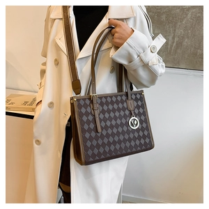 Detail of vintage patterned tote bag with brown leather trim and wide textile strap