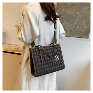 Detail of vintage patterned tote bag with brown leather straps on a white trench coat