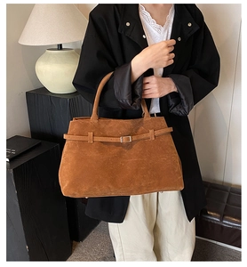 Detail of a brown frosted leather tote bag featuring adjustable metal buckle and strap