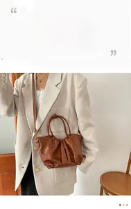 Détail d'un sac à main en cuir marron caramel avec poignée ronde et bandoulière fine