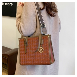 Detail of vintage brown tote bag with diamond lattice pattern and wide striped strap
