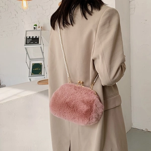 Pink plush crossbody bag with pearl chain and metallic clasp on a model's back