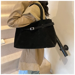 Detail of vintage matte black tote bag with buckle strap and protective metal feet