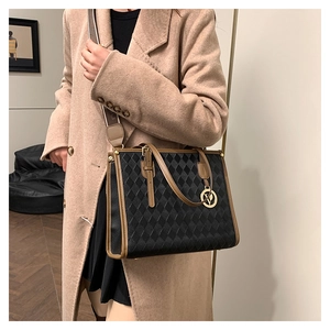Detail of vintage quilted tote bag with brown leather trim and golden logo charm