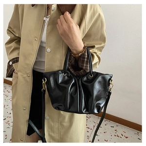 Détail du sac seau noir plissé avec anneau métallique et texture cuir PU brillante