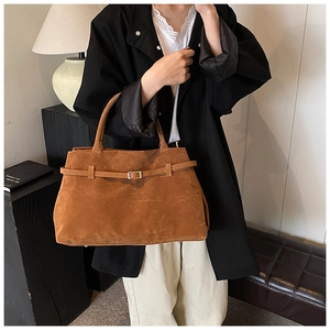 Detail of vintage caramel suede tote bag featuring decorative belt and metal buckle