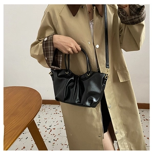 Détail du sac seau noir plissé avec poignées métalliques et fine bandoulière en cuir