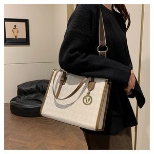 Detail of vintage-style quilted tote bag with wide strap and gold V logo pendant