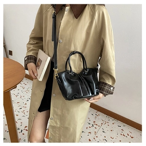 Détail d'un sac seau en cuir plissé noir avec anses rondes et finitions dorées