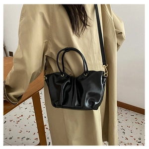 Détail du sac bandoulière noir plissé avec boucles dorées et poignées rondes sur un mannequin