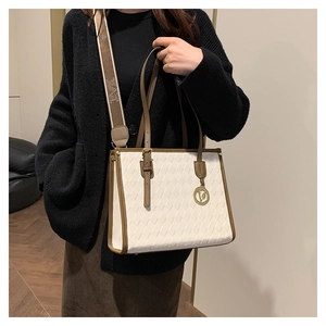 Detail of quilted tote bag with golden V-logo charm and patterned wide strap