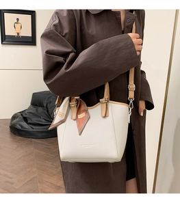 Détail d'un sac seau en cuir blanc avec poignée marron et foulard en soie imprimé