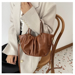 Sac panier plissé marron montrant la texture du cuir et les anneaux dorés sur modèle