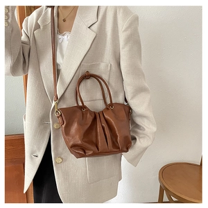 Sac panier en cuir plissé marron avec un blazer à carreaux beige dans un style de vie