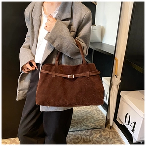 Detailed macro of dark brown matte suede tote bag with stylish silver buckle belt detail