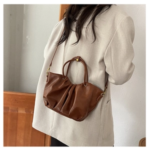 Détail d'un sac seau vintage plissé marron foncé avec finitions dorées et bandoulière en cuir