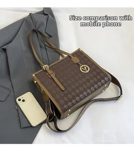 Brown quilted tote bag with wide strap compared to a smartphone for size scale