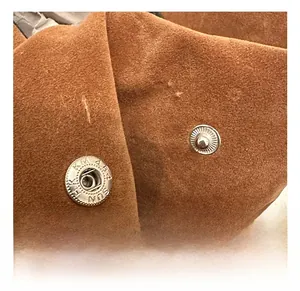 Close-up of silver metal snap buttons on a brown matte suede vintage tote bag