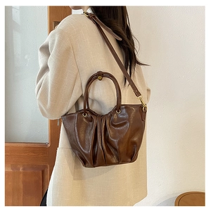 Sac cabas froncé marron à fini poli porté par un mannequin pour un look bandoulière chic