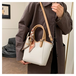 Détail du sac seau élégant avec poignée contrastée et foulard en soie décoratif chic