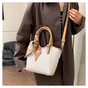Détail du sac seau en cuir beige avec bandoulière marron et foulard en soie à fleurs