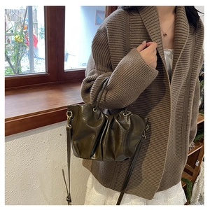 Sac nuage plissé vert olive chic porté avec un gilet en maille et une jupe en dentelle