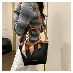 Gros plan d'un sac seau en cuir noir avec foulard en soie décoratif sur la poignée