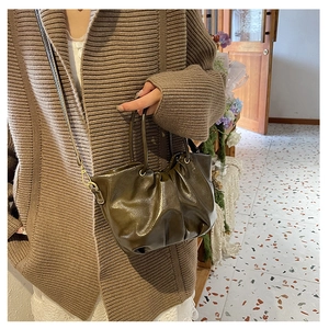 Détail du sac plissé en cuir vert olive foncé fini brillant sur maille marron