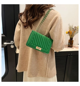 Detail of green quilted leather crossbody bag with gold chain strap and turn-lock