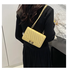 Detail of golden chain strap and diagonal quilted texture on women's shoulder bag