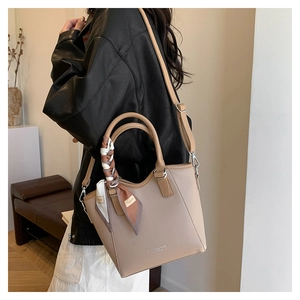 Gros plan du sac seau en cuir beige avec foulard en soie stylé sur la poignée