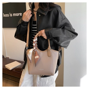 Détail du sac cabas beige en cuir grainé avec une poignée ornée d'un foulard décoratif