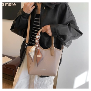 Détail d'un sac seau en cuir grainé marron clair avec foulard en soie décoratif sur l'anse