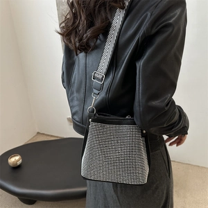 Fashionable black rhinestone bucket bag with woven wide shoulder strap shown on model