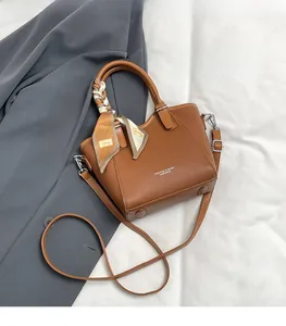 Détail du sac seau marron en cuir grainé avec foulard décoratif en soie sur la poignée