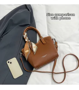 Détail du sac seau marron en cuir grainé avec foulard en soie et bandoulière réglable