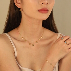 Golden shell jewelry set with necklace bracelet and turquoise ring on a female model