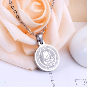 Macro detail of silver Saint Benedict medal necklace with rose petals background