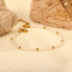 Elegant white pearl bracelet with gold steel beads and adjustable clasp on stone