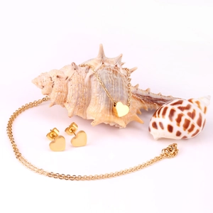 Minimalist gold heart jewelry set with necklace and earrings on a sea shell background