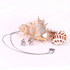 Macro detail of silver heart necklace and stud earrings set on decorative seashells