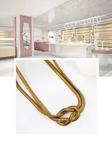 Détail du collier double chaîne serpent en acier plaqué or 18 carats avec motif nœud chic