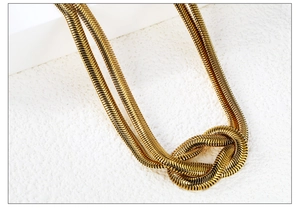 Vue macro d'une chaîne serpent en acier plaqué or 18K avec détail de nœud décoratif