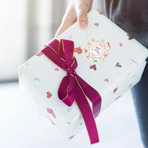 Detailed view of Thank You floral sticker sealing a gift box with a purple silk ribbon